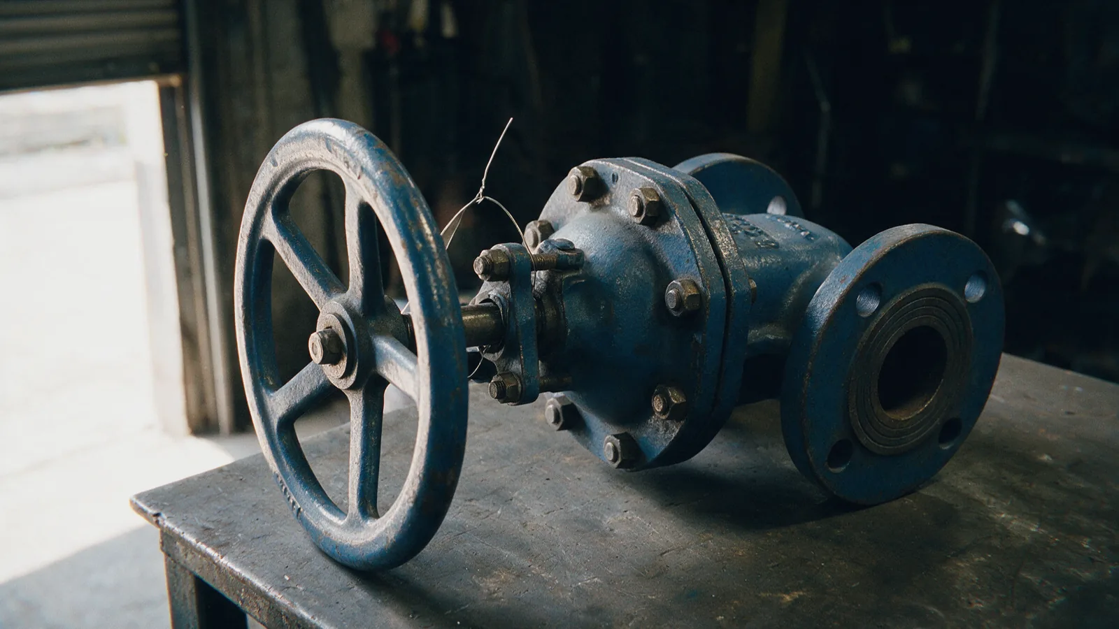 Flanged cast-iron gate valve with a spoked handwheel on a workshop bench